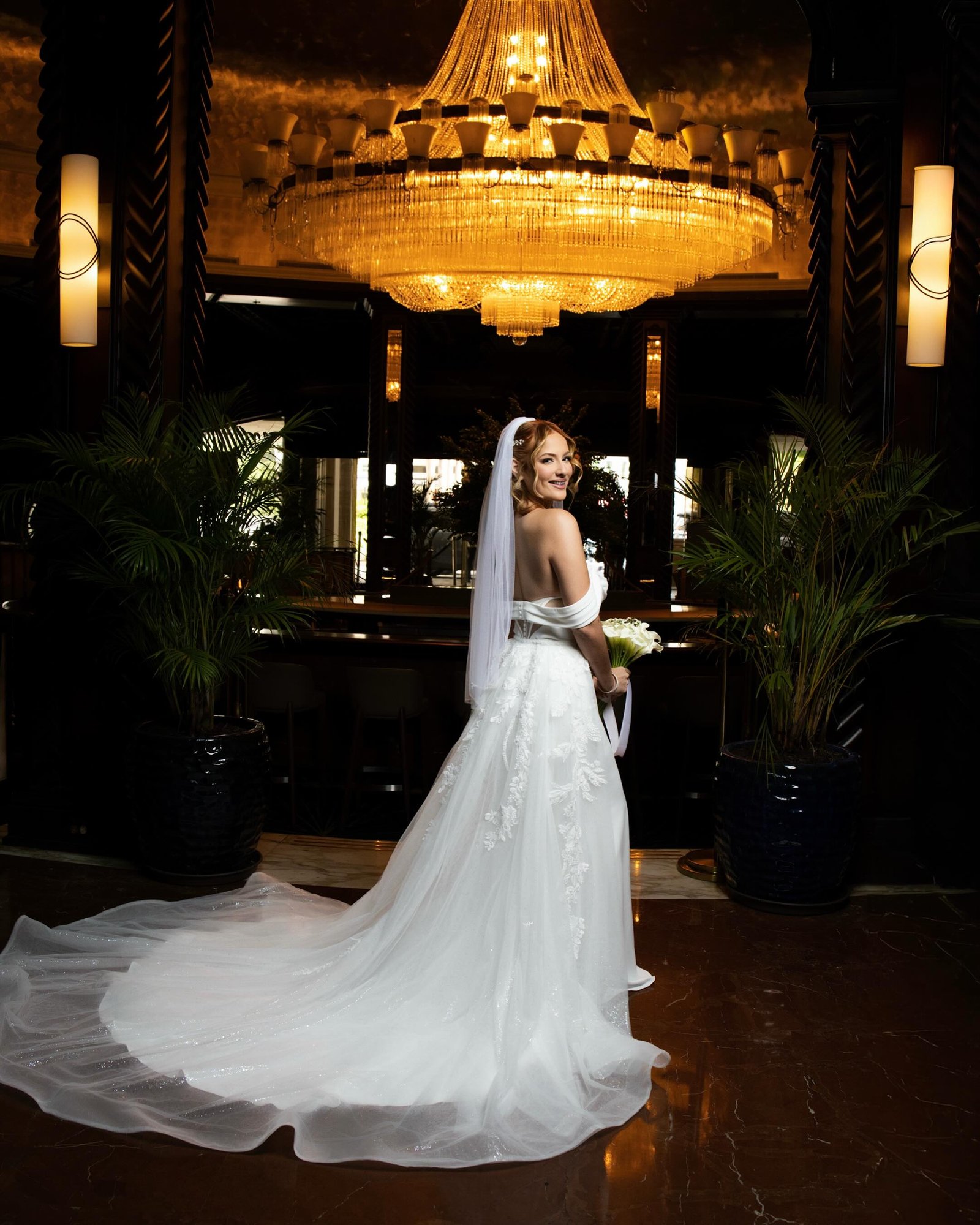 Bride posing beneath a grand golden chandelier